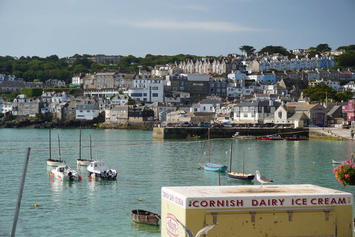 A harbour town with boats on turquoise water and an ice cream van in front