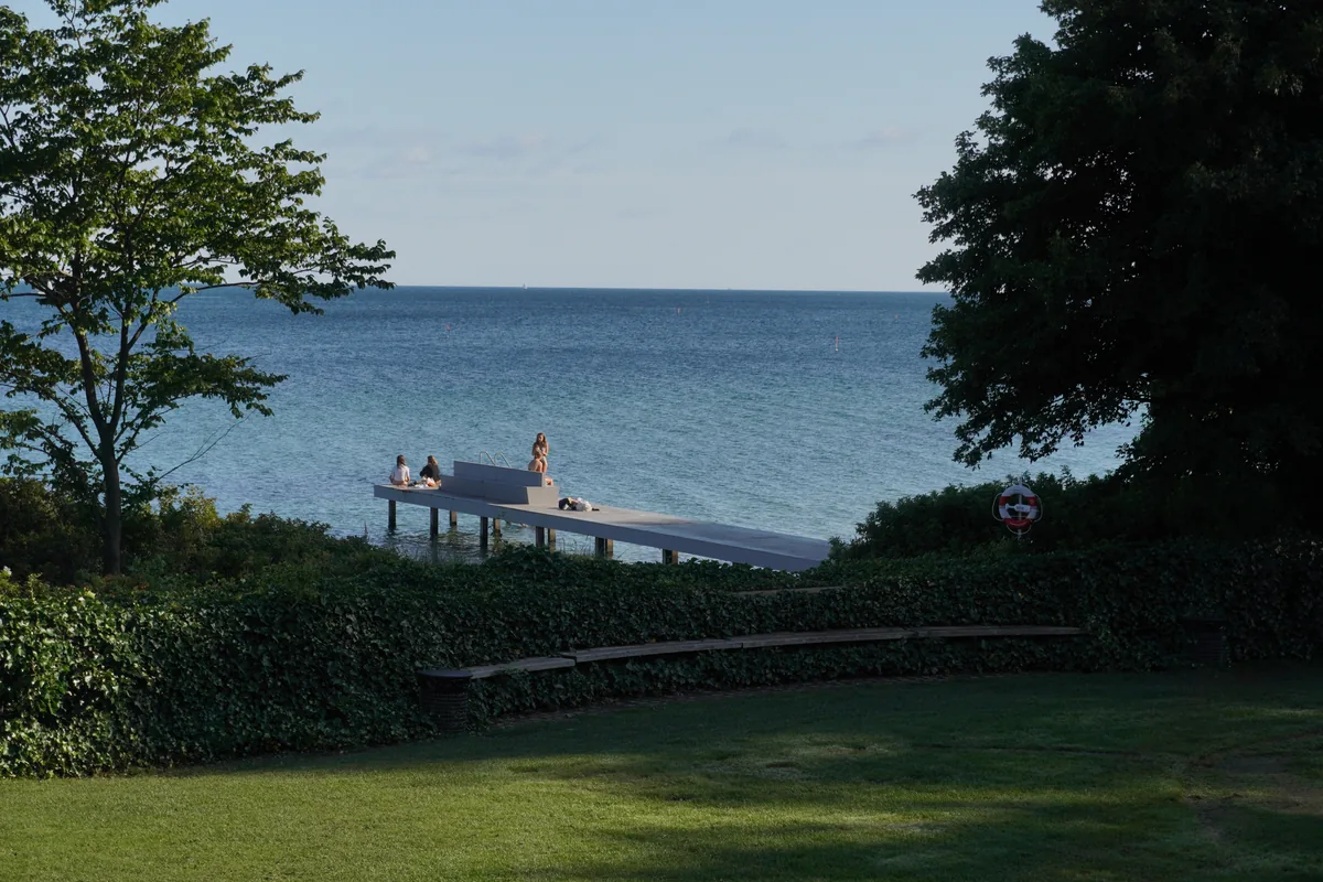A bathing jetty seen between trees, with the sea beyond