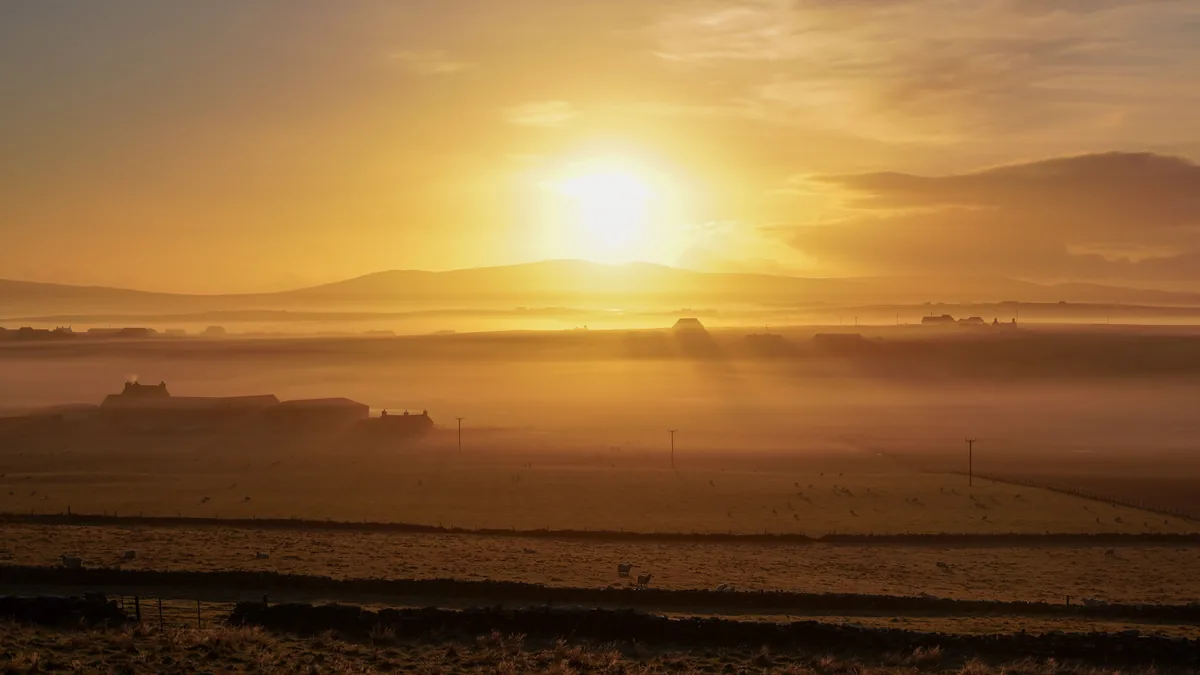 A golden sunrise over misty fields