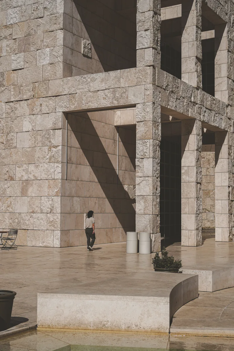 A small figure walking beneath a monumental stone building