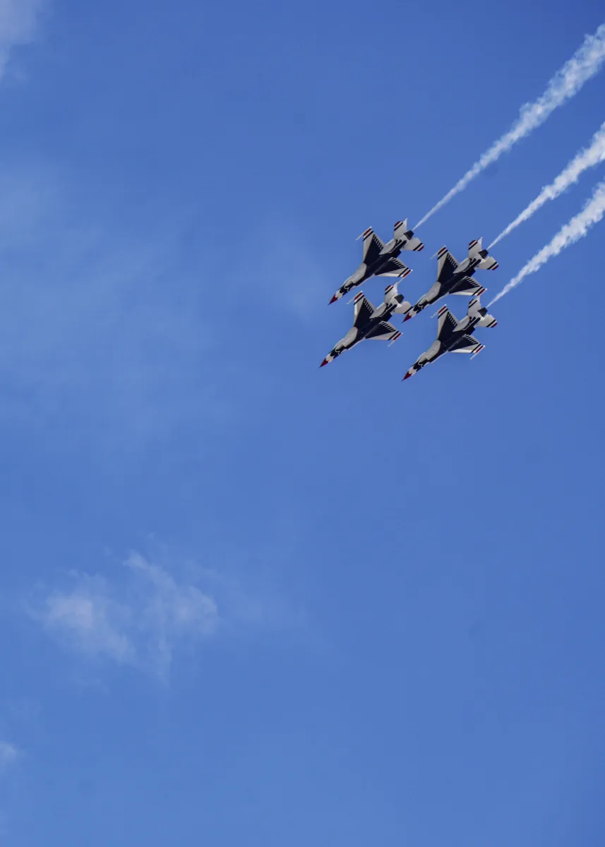 Four jets in tight formation trailing smoke in a blue sky